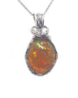 Oval Ethiopian opal pendant with vibrant play of colors and brown pinpoint fire, set in handcrafted silver wire wrap.