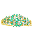 topside view of a gold bangle bracelet with natura emeralds and diamonds.