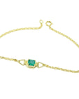 Gold bracelet with a solitaire Muzo colombian emerald on a white background.
