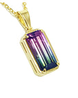 Gold pendant with a colorful watermelon tourmaline gemstone on a white background.