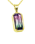 Gold pendant with a multicolored tourmaline gemstone on a white background.