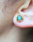 Close-up of an ear wearing a tulip emerald stud earring.
