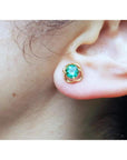 Close-up of an ear wearing a tulip natural emerald stud earring.