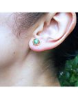 Colombian emerald tulip stud earrings in 14K yellow gold, worn on an ear.