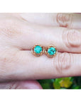 Colombian emerald tulip stud earrings in 14K yellow gold with round-cut green emeralds.