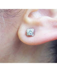 A woman's ear wearing a 14k white gold diamond stud earring, tulip style.