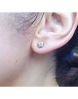 0.59 ct. round diamond tulip stud earrings in 14K white gold on an ear.