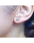 0.59 ct. round diamond tulip stud earrings in 14K white gold on an ear.
