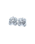 A pair of white gold diamond stud earrings with a round cut and tulip prong set style, featuring accent diamond petals.