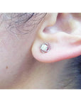 An earlobe wearing a bride's diamond tulip earring in white gold.