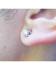 White gold tulip stud earring with a round natural diamond, worn on an ear.