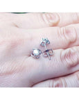 White gold natural diamond tulip stud earrings with round cut diamonds on a hand.