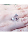 White gold natural diamond tulip stud earrings with round cut diamonds on a hand.