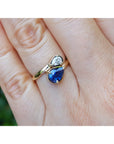 Two-stone "You and Me" blue natural sapphire bypass ring with a teardrop diamond on the side, handcrafted in 18k yellow gold.
