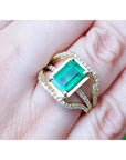 Toma grafica cercana de una mano exhibiendo un anillo de oro amarillo con esmeralda rectangular y diamantes laterales.
