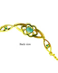 The downside view of a gold bracelet with genuine emeralds on a white background.