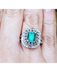 A vintage Colombian emerald ring with accent diamonds on a finger.