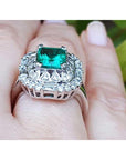 Vintage ring with a colombian emerald and diamond accents on a finger.