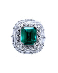 This vintage-style Colombian emerald ring features a square emerald cut, encircled by sparkling diamonds, and crafted from 14k white gold.