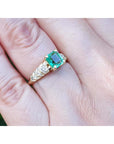 Vintage emerald and diamond ring in 14K yellow gold on a hand.