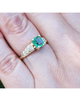 Vintage emerald and diamond ring in 14K yellow gold on a hand.