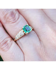 Vintage emerald and diamond ring in 14K yellow gold on a hand.