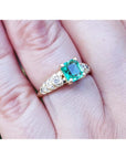 Vintage 14K yellow gold ring with a sparkling emerald-cut green emerald and accent diamonds on a finger.