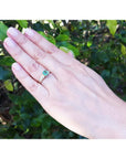 Vintage emerald and diamond ring in 14K yellow gold on a woman's hand.