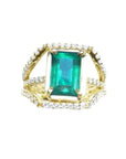 Anillo de oro amarillo para mujer con esmeralda rectangular sobre tres líneas de diamantes naturales.