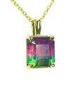 Multicolored tourmaline gemstone pendant on a gold chain against a white background.