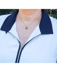White sleeveless top with navy collar and zipper, worn by a person outdoors.