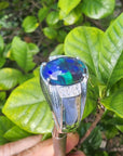 A men's black opal sterling silver ring in held against green leaves