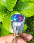 Silver ring for men with a colorful Ethiopian black opal held against green leaves