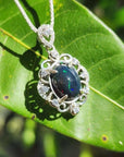 Multicolor Welo Ethiopian black opal pendant in sterling silver with CZ accents on a green leaf.