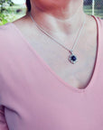 Woman wearing a black Ethiopian Welo opal pendant with multicolor fire, set in sterling silver.