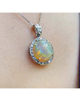Ethiopian Welo opal pendant with red flashes, diamond halo, and 14K white gold chain on a person.
