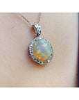 Ethiopian Welo opal pendant with red flashes, diamond halo, and 14K white gold chain on a person.