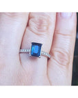 Blue sapphire ring white gold showcasing a rich deep blue hue. Accented with natural diamonds along the sides, on a finger.