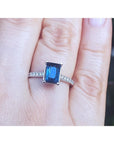 Blue sapphire ring white gold on a finger against a blurred background