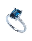 18K white gold ring with a radiant-cut blue sapphire and diamond accents.