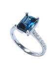 18K white gold ring with a radiant-cut blue sapphire and diamond accents.