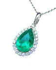 Emerald teardrop pendant with diamond halo on a white background