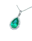Emerald teardrop pendant with diamond halo on a white background