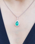 Emerald teardrop pendant on a white gold chain against a dark blue background