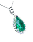 A natural emerald pendant with white gold chain on a white background