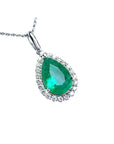 Emerald green teardrop pendant with diamond accents on a right-side position displaying topside view