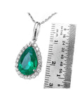 18K white gold pear-shaped emerald pendant with diamond halo, next to a ruler.