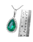18K white gold pear-shaped emerald pendant with diamond halo, next to a ruler.