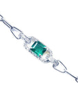 A 14k white gold paperclip bracelet with a natural colombian emerald and diamonds.