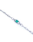 A white gold paperclip bracelet with a colombian emerald on a top far view.